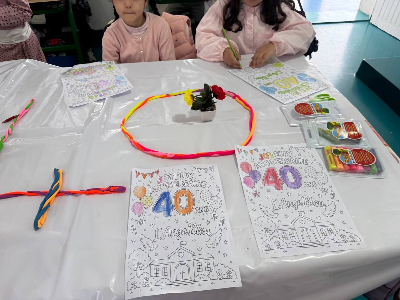 Coloriages « Joyeux anniversaire, 40 ans, L'Ange Bleu » et créations en pâte à modeler posés sur une table.